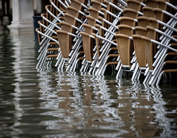 Brown stacked chairs on water filled walkway during flood at piazza san marco