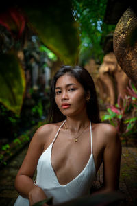 Portrait of young woman standing against trees