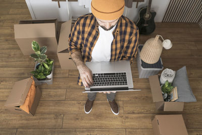 Happy mature man in a newly rented ore purchased apartment using a laptop.