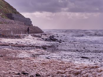 Man and dog watching rough sea. irish sea, uk.