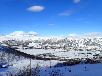 Scenic view of snow covered mountains against blue sky