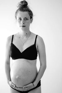 Portrait of pregnant woman standing against white background