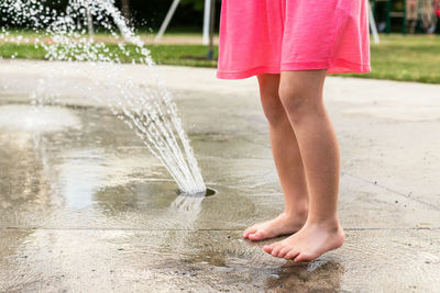 Low section of girl standing by fountain