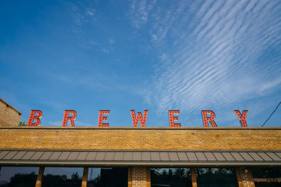 Low angle view of information sign against blue sky