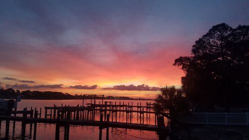 Silhouette bridge over sea against sky during sunset