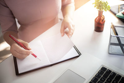 Midsection of woman using mobile phone on table
