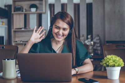 Young woman using phone while sitting on table