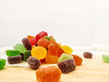 Close-up of multi colored candies on table against white background