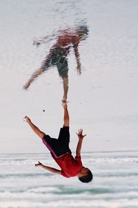 Upside down image of boy standing on shore at beach