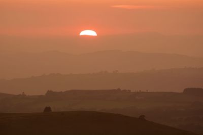 Scenic view of silhouette mountains against orange sky