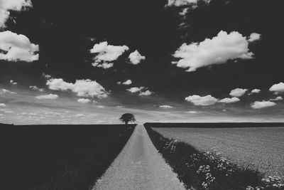 Road amidst field against sky