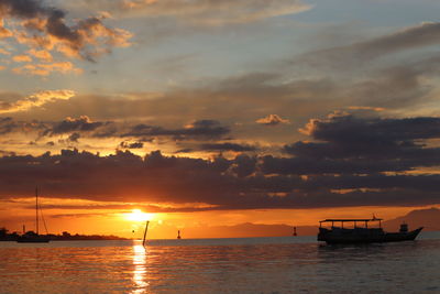 Silhouette sailboats in sea against sky during sunset