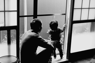 Rear view of couple standing in glass window