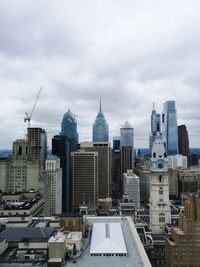 Buildings in city against cloudy sky