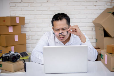 Young man using mobile phone while sitting on table