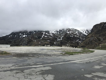 Road by snowcapped mountains against sky