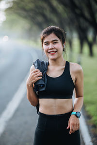 Young asian women drink water and stand to rest after jogging a morning workout in the city. 