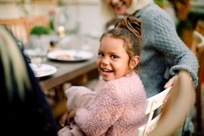 Portrait of smiling girl sitting with grandmother by dining table during lunch