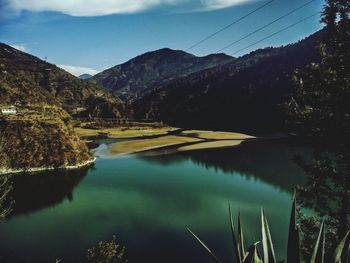 Scenic view of river by mountains against sky