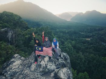 Portrait of smiling women sitting with flag on rock