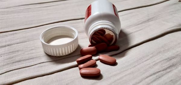 Close-up of medicine spilling from bottle on table