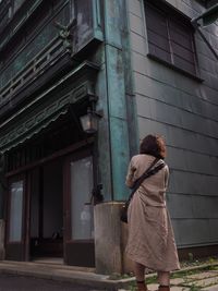 Rear view of woman standing against building