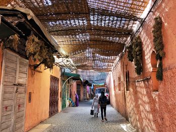 Rear view of man walking on street amidst buildings in city