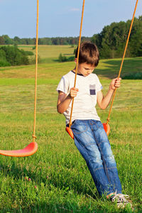 Sad boy sitting on swing at playground