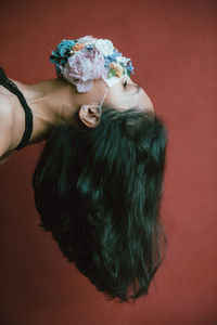 High angle view of woman holding flower bouquet against red background