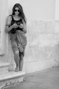 Portrait of young woman standing against wall