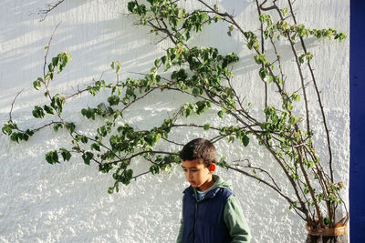 Portrait of young man standing against plants in winter