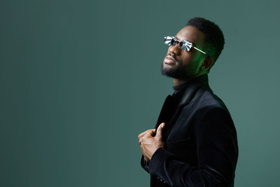 Portrait of young man standing against black background