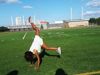 Cheerleader practicing cartwheel at american football field