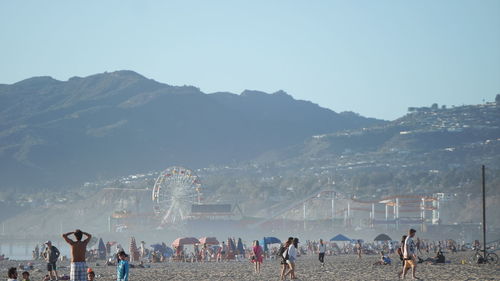 People at sandy beach against clear sky