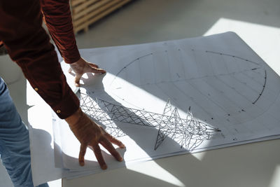 Hands of businessman by electric pylon model on blueprint at desk