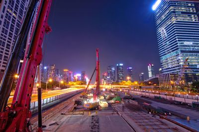 Light trails on road amidst buildings against sky at night