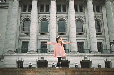 Low angle view of woman standing against historic building