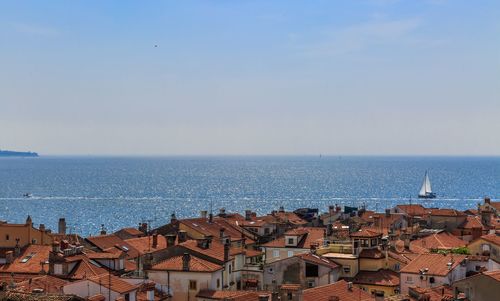 Cityscape by sea against clear sky