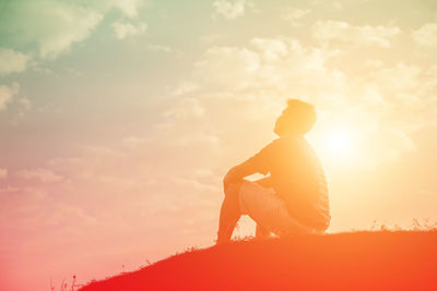 Low angle view of silhouette man sitting against sky during sunset