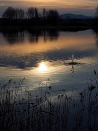 Scenic view of lake against sky at sunset