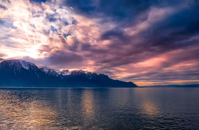 Scenic view of lake by mountains against sky during sunset