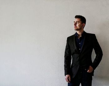 Young man looking away while standing on wall