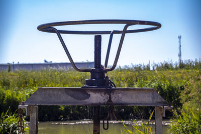 Close-up of old machinery on field against clear sky