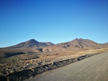 Scenic view of arid landscape against clear blue sky