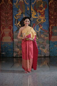 Portrait of a smiling young woman standing against tiled floor