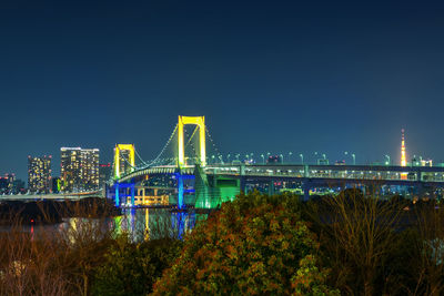 Illuminated bridge over river in city