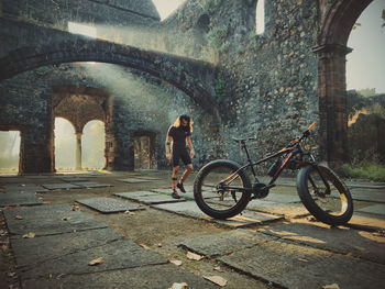 Side view of man with bicycle standing against wall