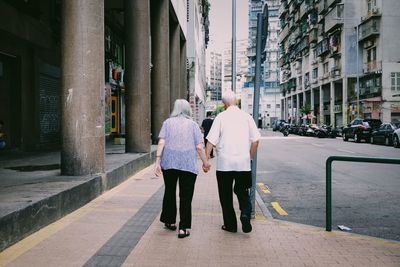 Rear view of friends walking on street in city