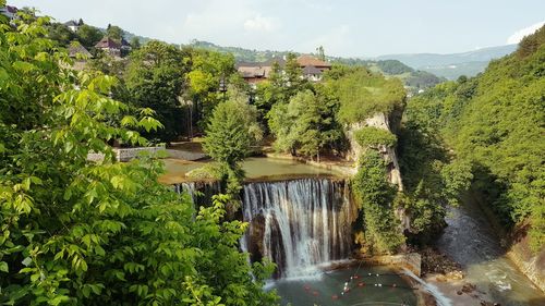 Scenic view of waterfall in forest against sky