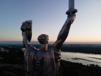 Statue against sky in city at sunset